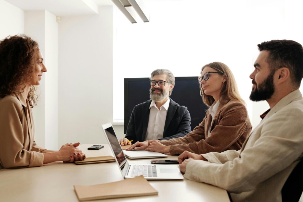 Group of professionals in a business meeting discussing strategies around a table in an office setting.